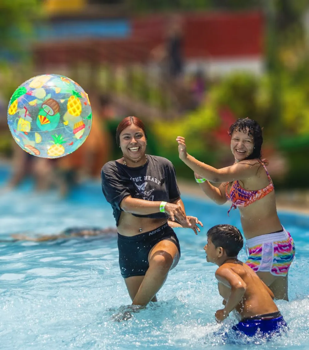 Familia jugando con una pelota de playa en la piscina