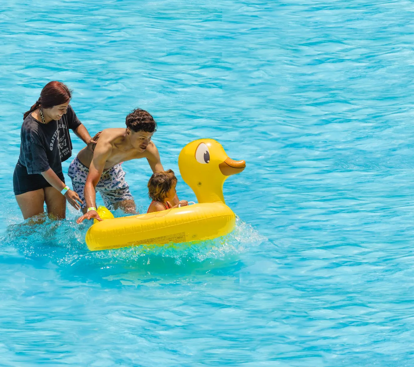 Papá y dos niños jugando con un flotador de pato en la piscina