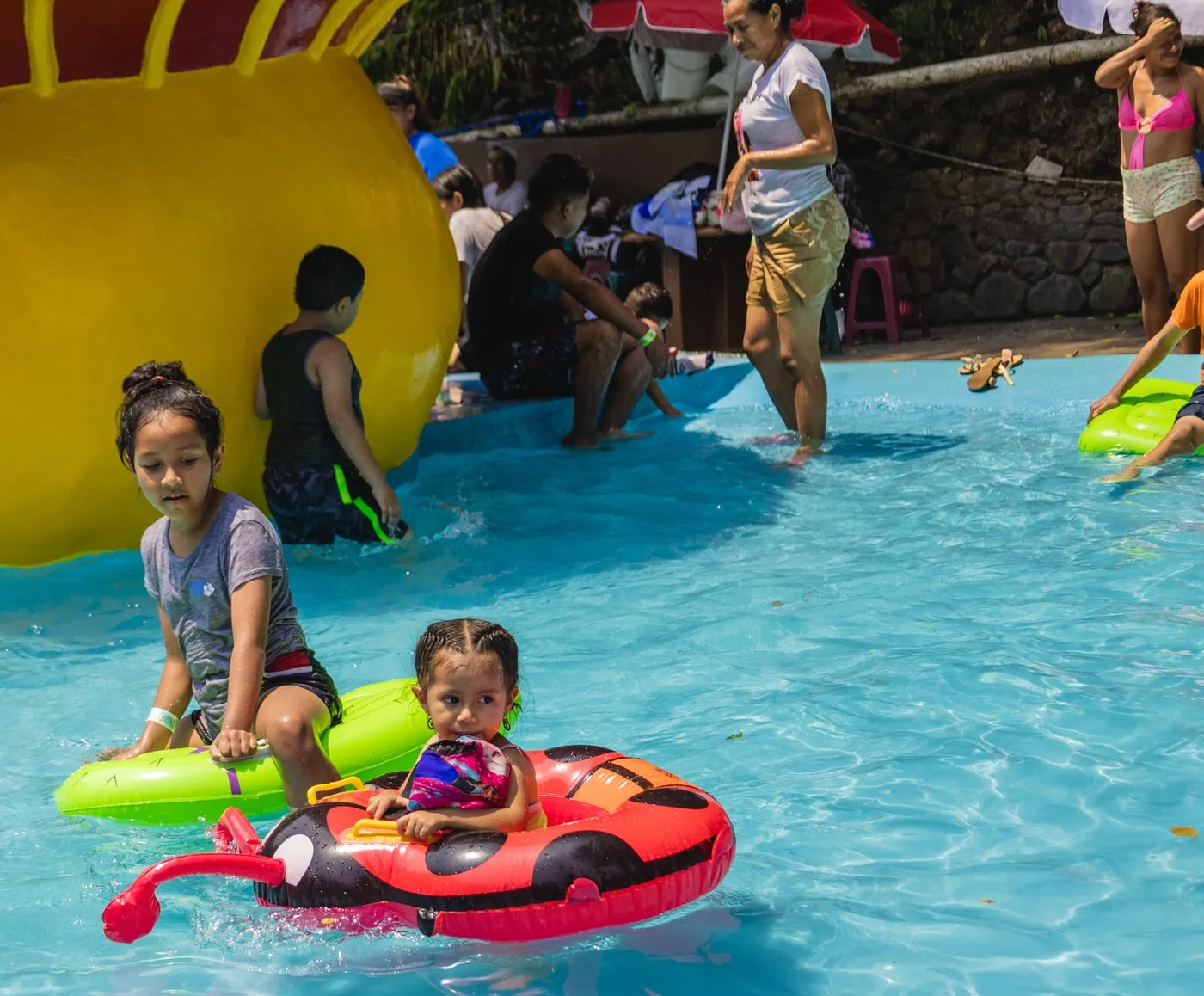Niños con flotadores en la piscina baja del parque