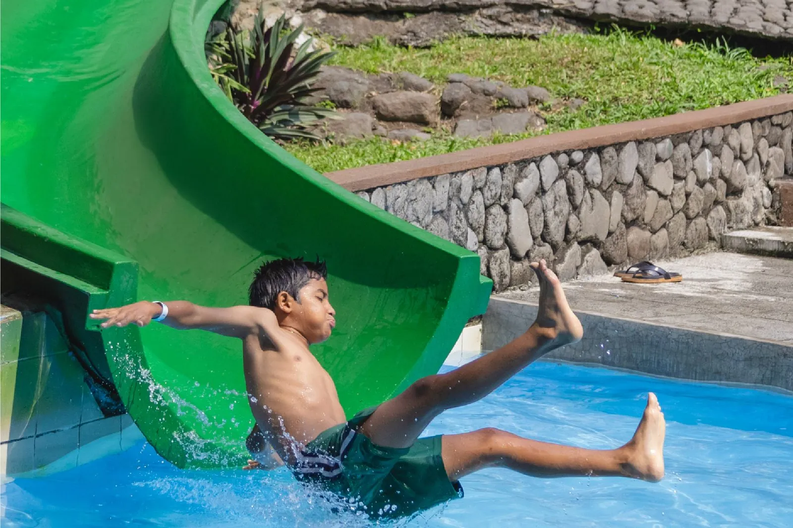 Niño bajando por el tobogán verde de Aqua Park